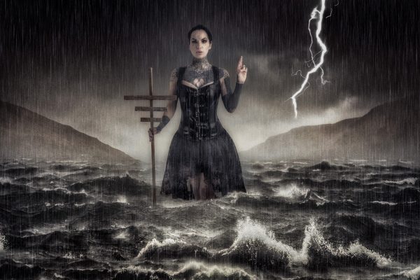 fine art image of a woman in a Victorian dress surrounded by choppy waters and a stormy sky. She's holding a staff and has her left hand raised