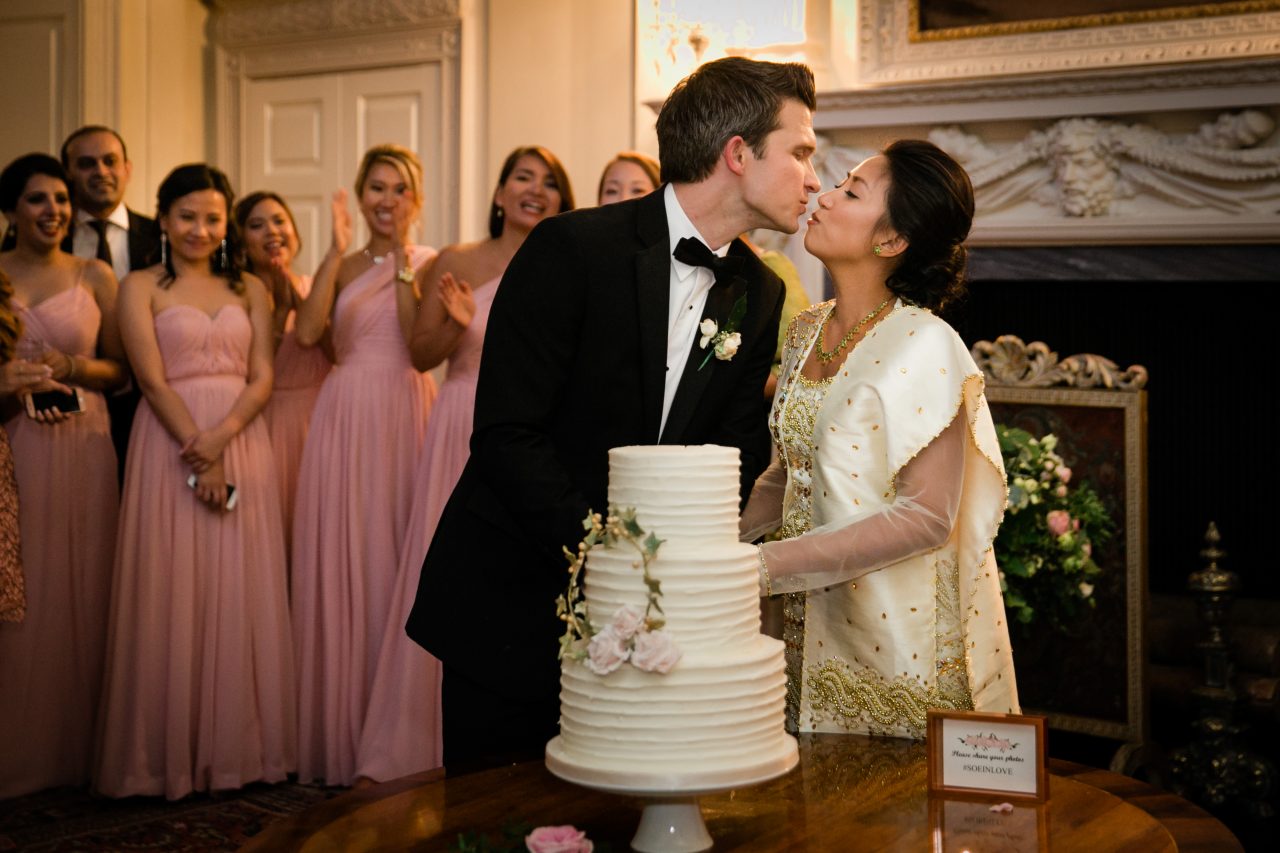 bride and groom kissing in front of wedding cake